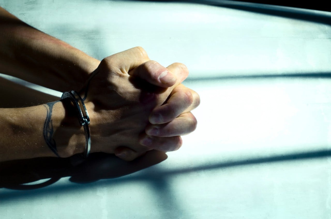 A man's hands cuffed on a table. Image: iStock