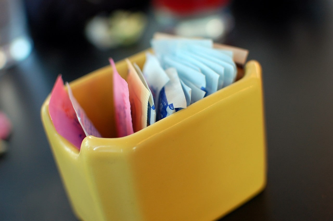 A photo of packets of artificial sweetener in a container