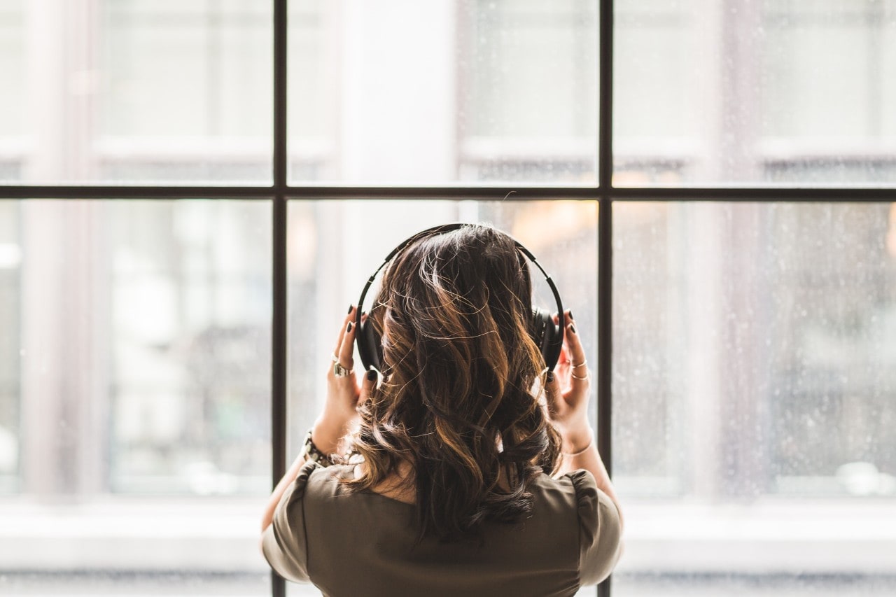 A woman with headphones on, listening to music.
