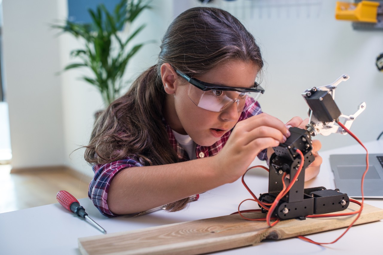 A young student repairs a robotic arm. Image: iStock