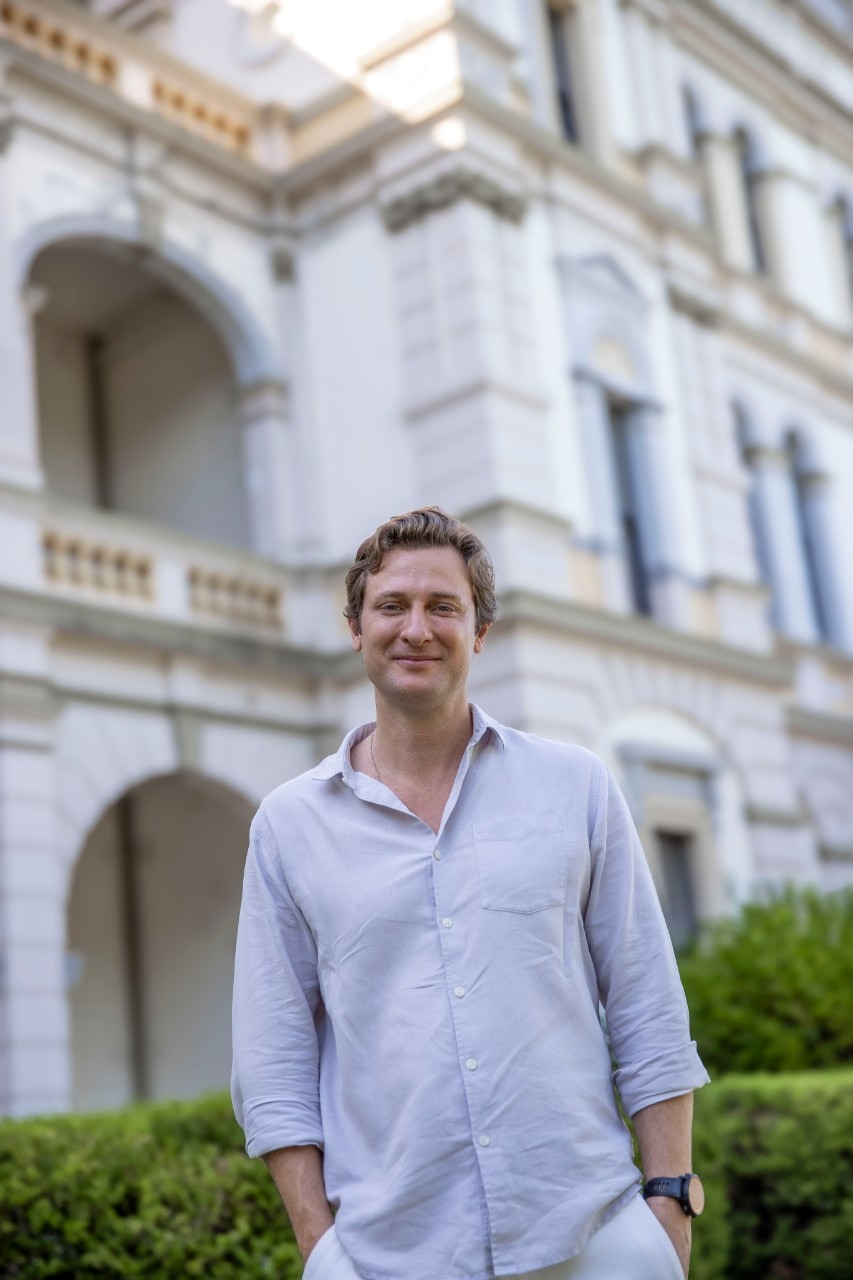 Ben King smiling while posing in front of a campus building