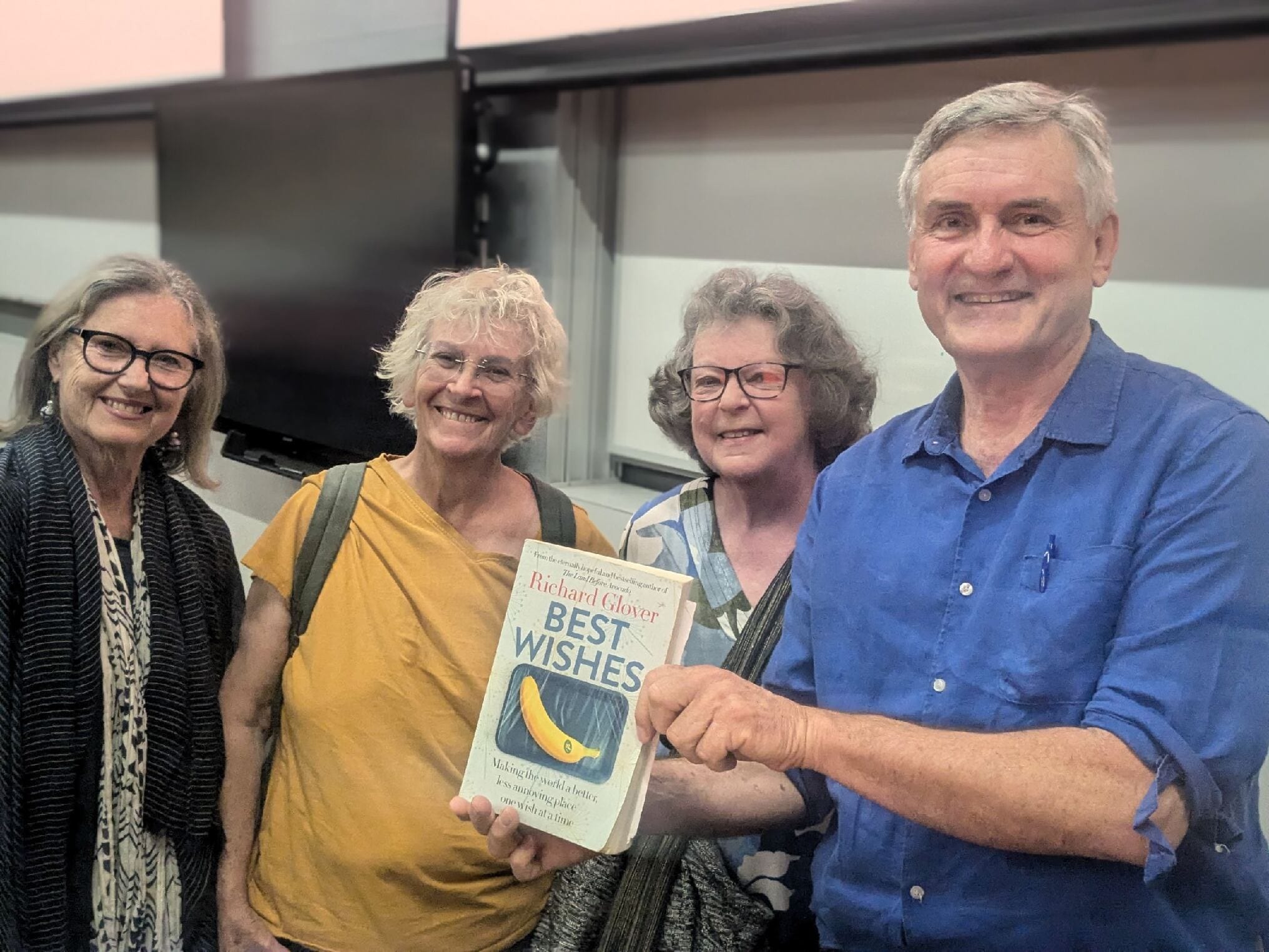 Richard Glover holding his book "Best Wishes" posed with three alumni