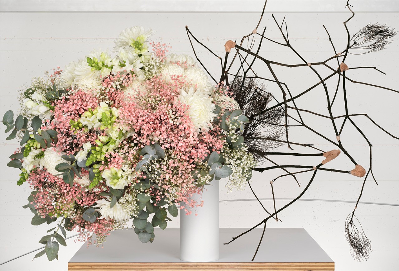 a bunch of pink flowers in a vase with burned sticks for contrast