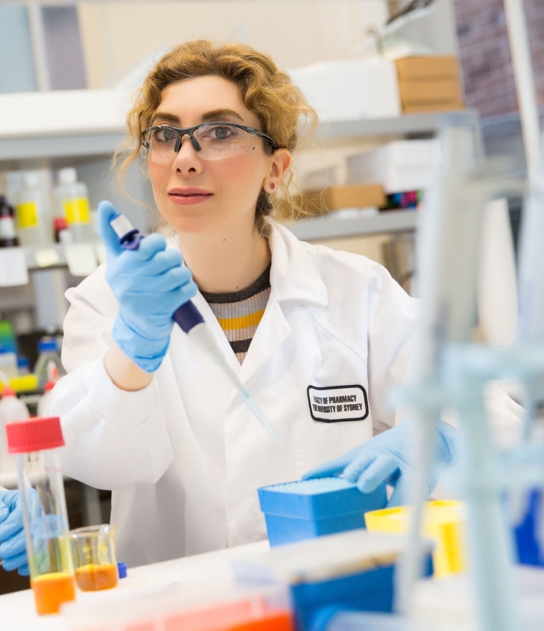 Dr Pegah Varamini is wearing a white coat and holding a test tube