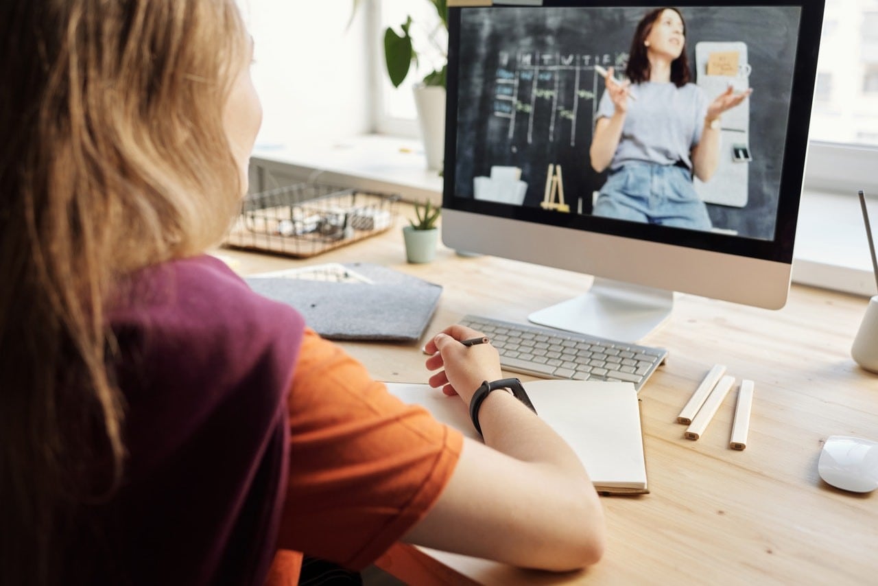 A woman in front of a laptop looking at another woman speaking on the screen