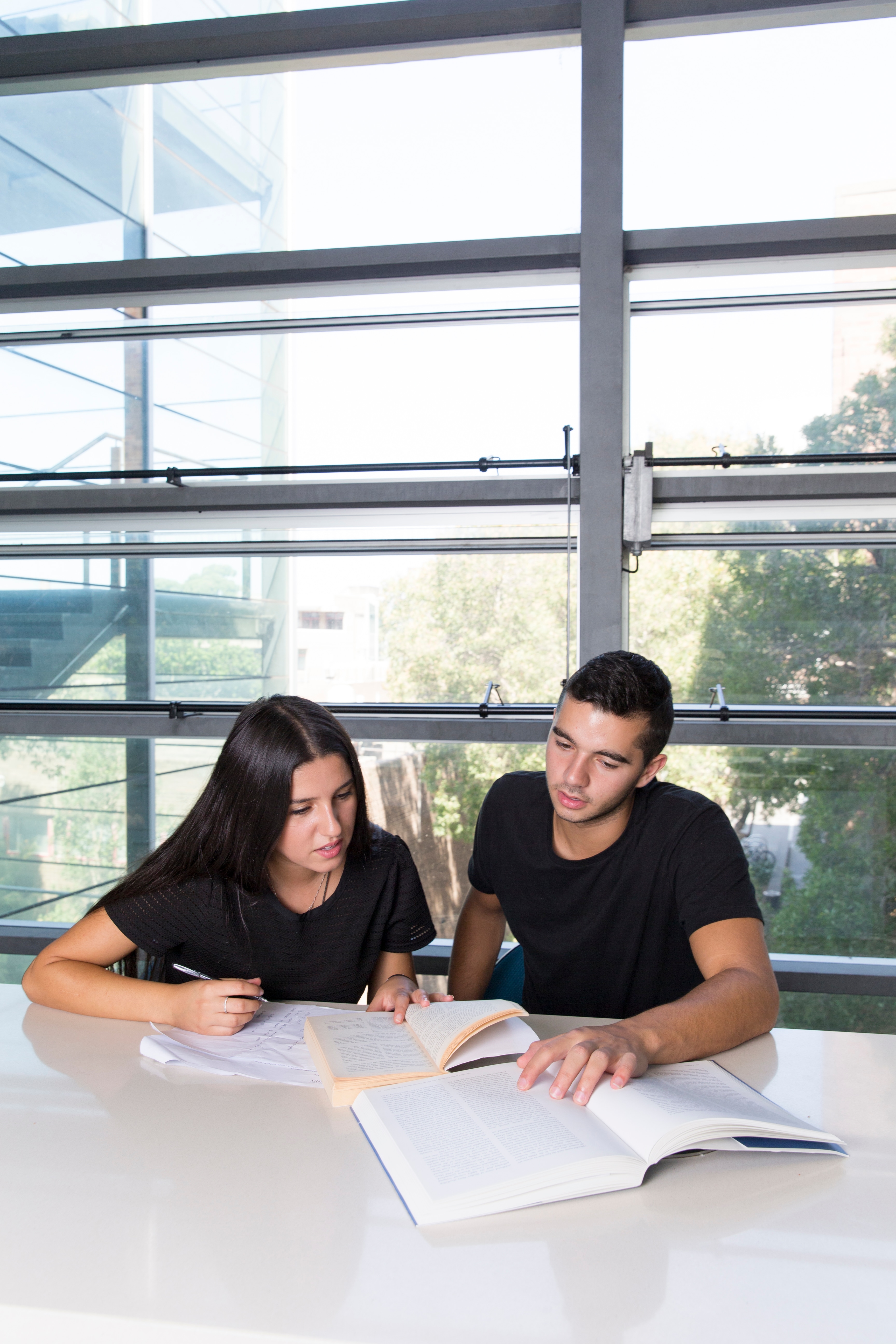 Male and female student in black studying