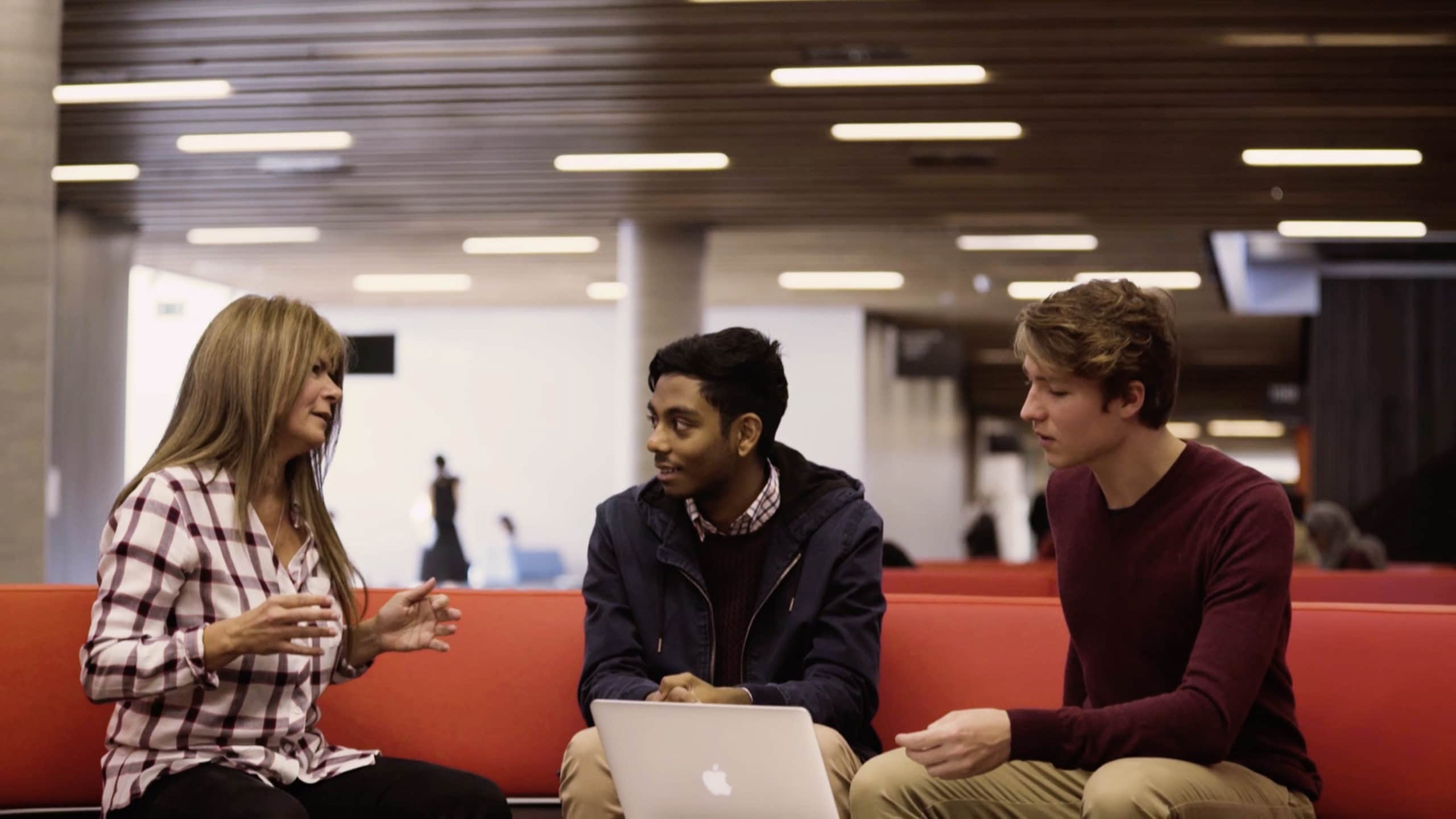 Three people sitting in front of laptop speaking casually