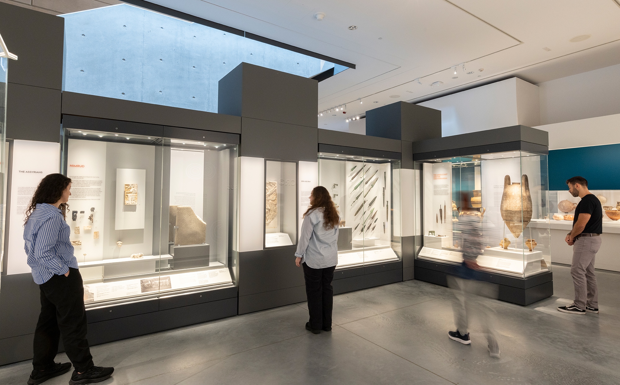 Three people look at the cabinets as part of the Ancient Cultures of the Middle East exhibition