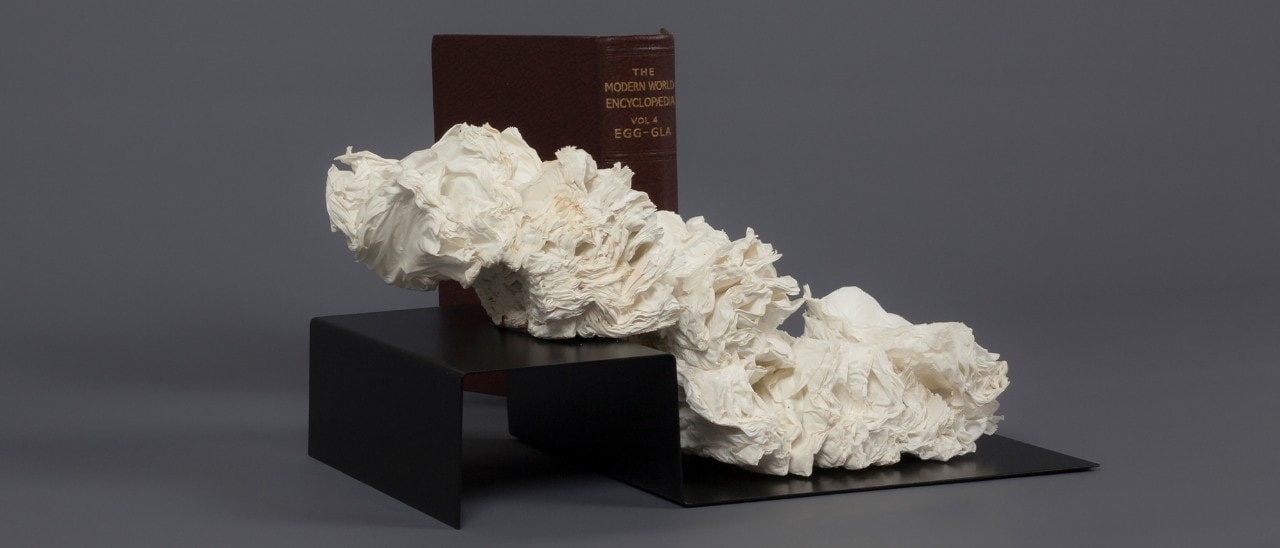 A white sculpture sitting in front of a book.