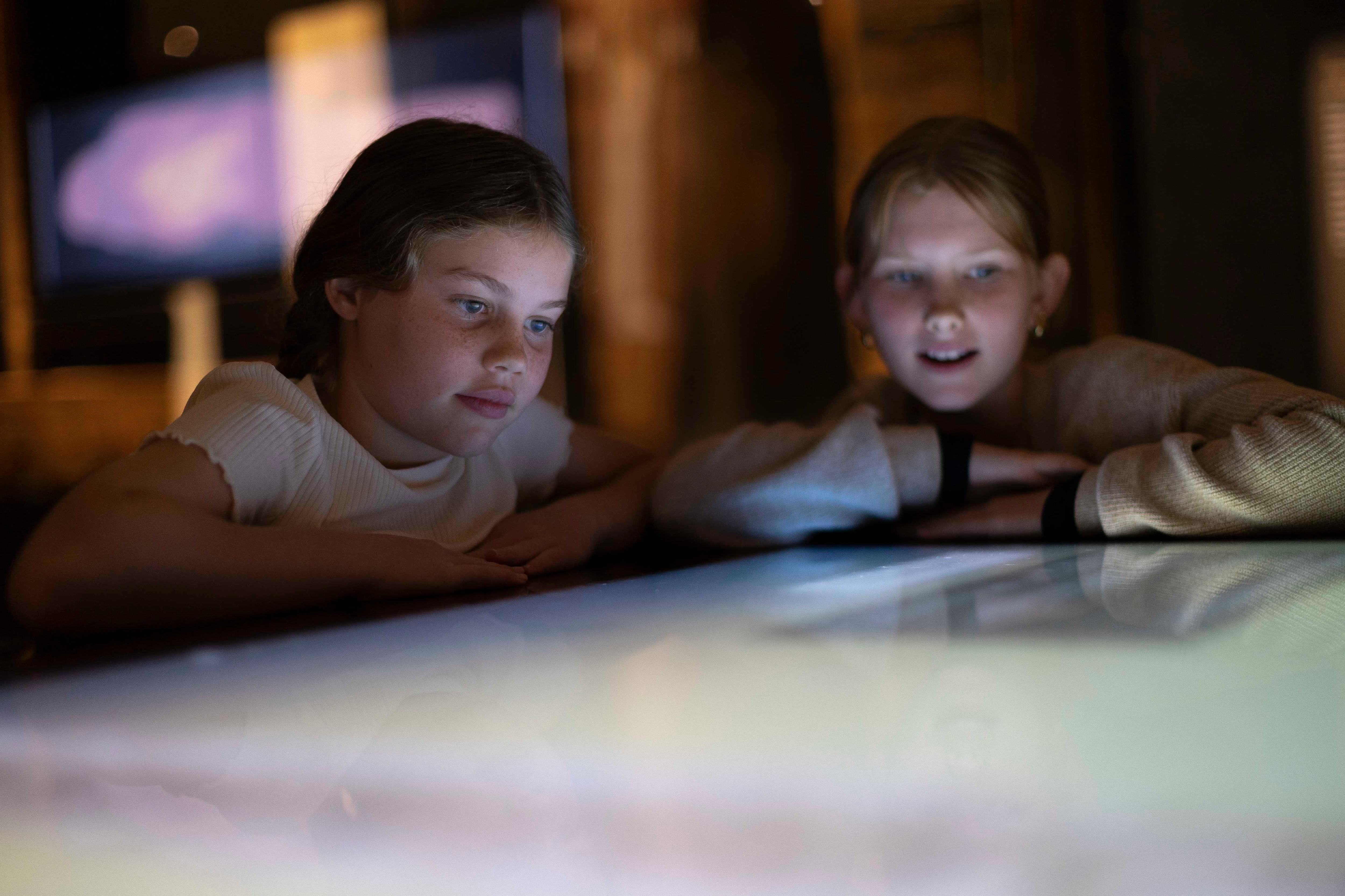 Two children look at a screen within 'The Mummy Room' exhibition at the Chau Chak Wing Museum