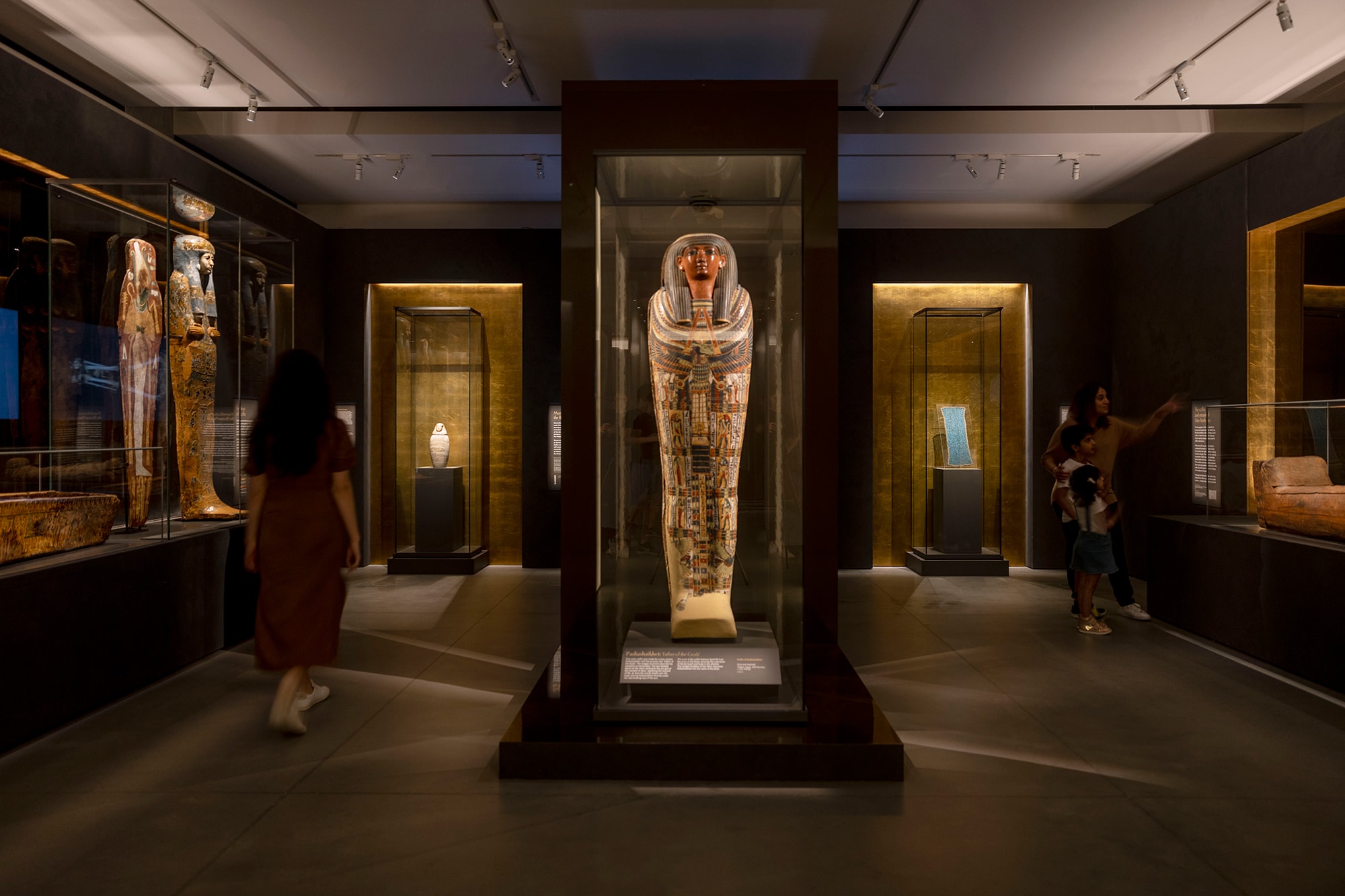 A blurred figure walks through 'The Mummy Room' at the Chau Chak Wing Museum