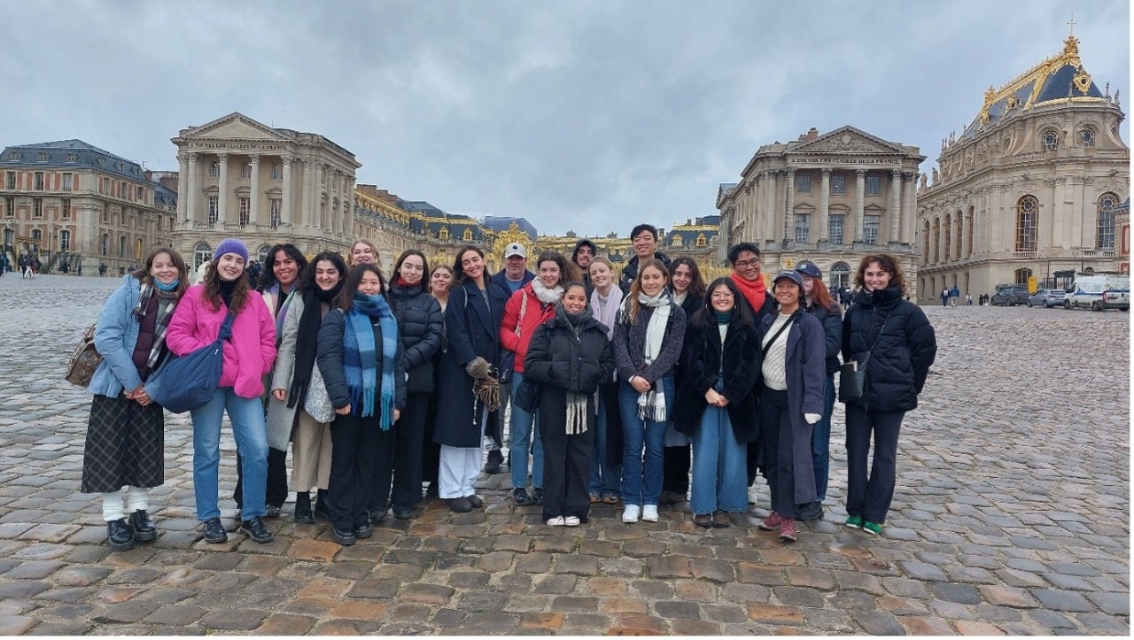 Group portrait at Versailles in front of the gates, with the chapel in the background.