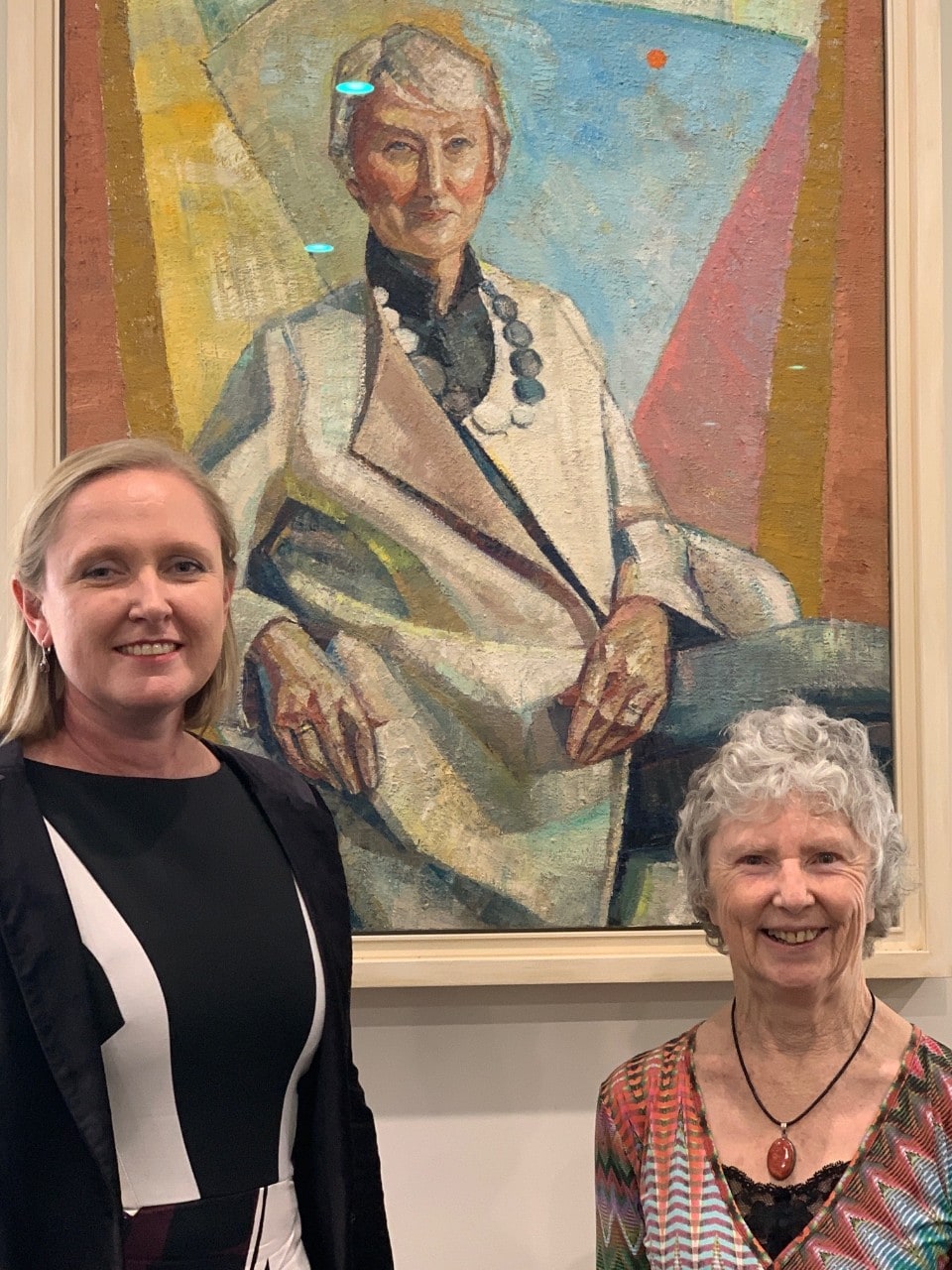 Darian McBain and Joy Murray standing in front of Yvette Coppersmith's portrait of Emeritus Professor Anne Green, President of Sydney’s Physics Foundation.