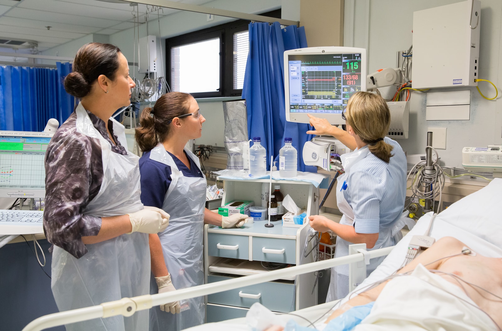 nurses checking heart rate monitor in hospital room