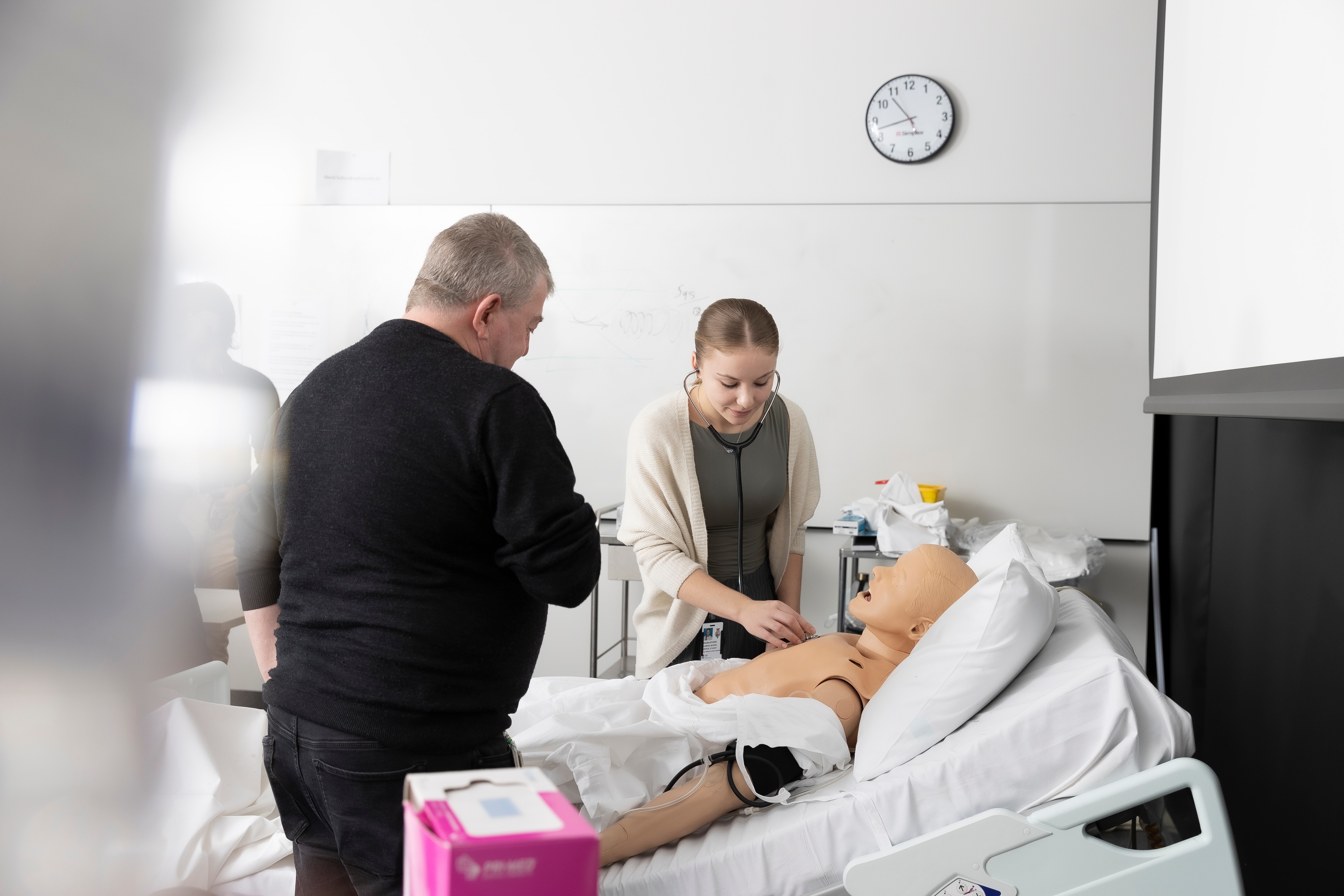 medical student using stethoscope to listen to simulation doll's heartbeat