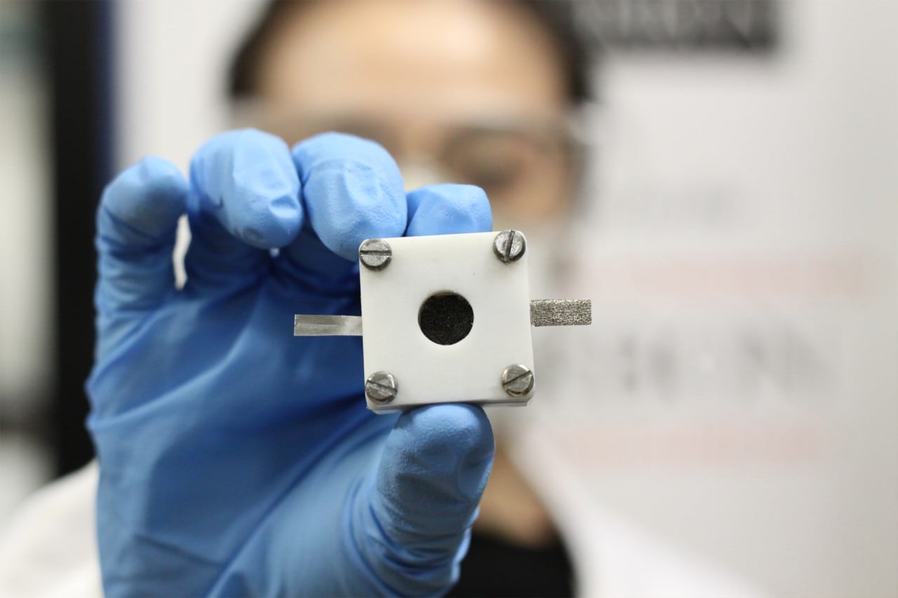 A University of Sydney researcher holds up a rechargeable zinc-air battery.