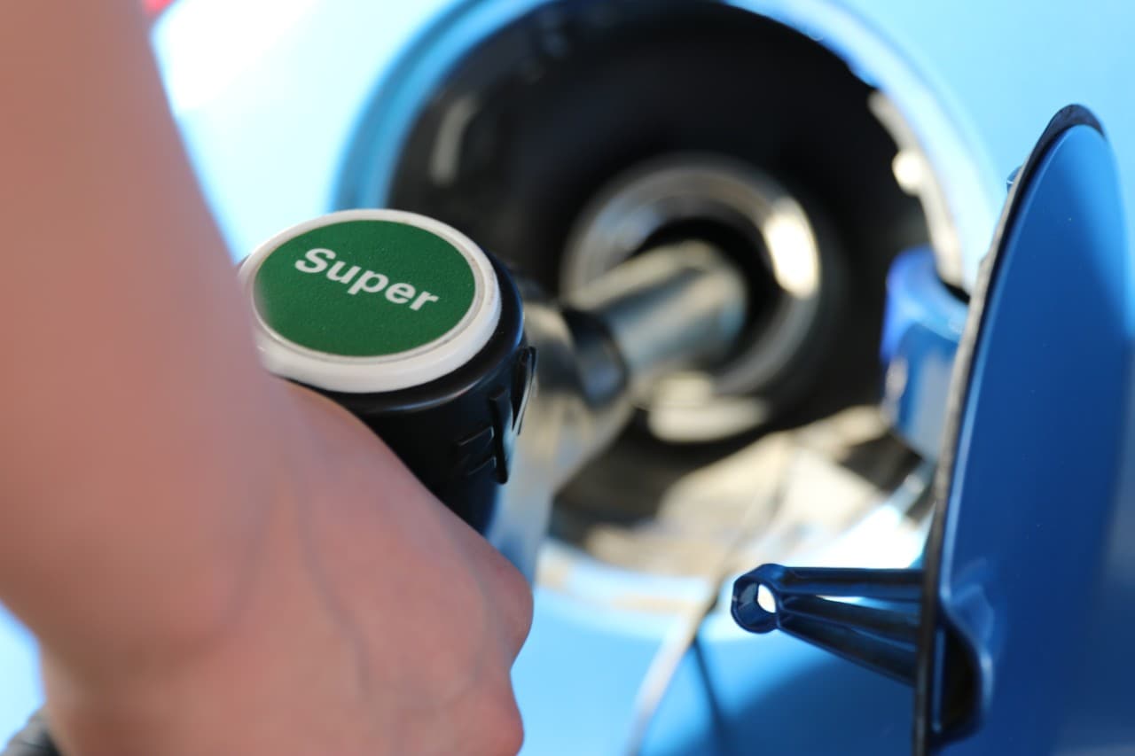 This image shows a hand holding a petrol pump refuelling a car.