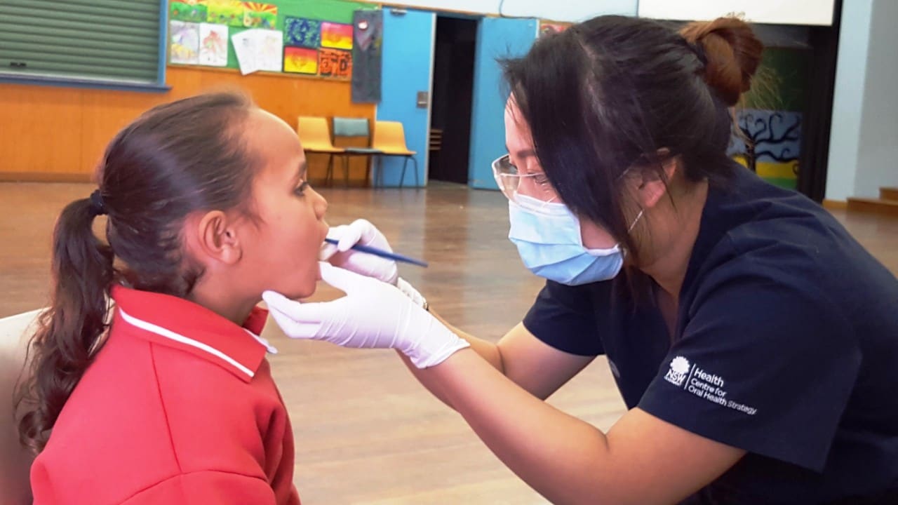 A student having their teeth checked by a health worker.