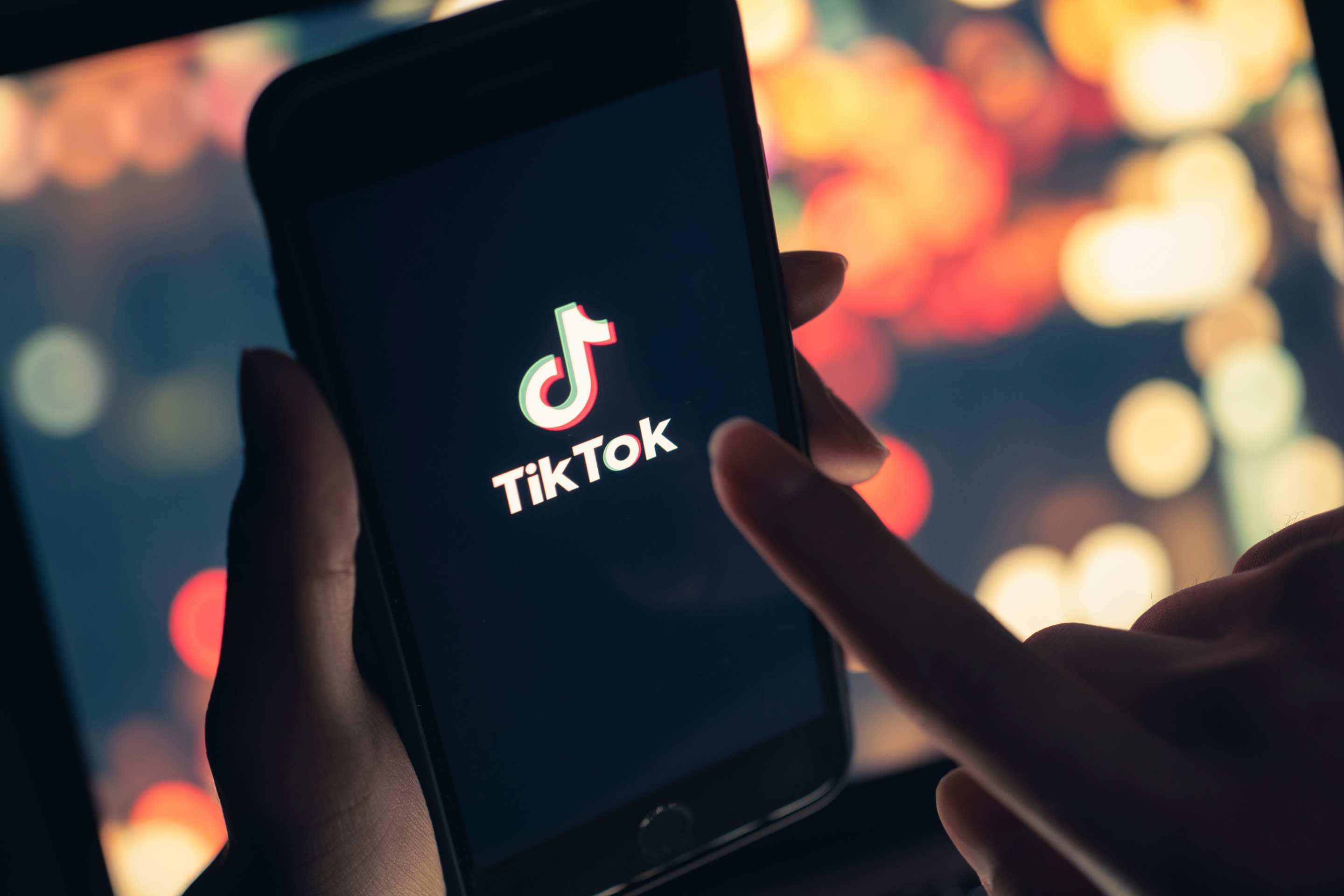 A hand holding a phone with the TikTok logo on the phone's screen.