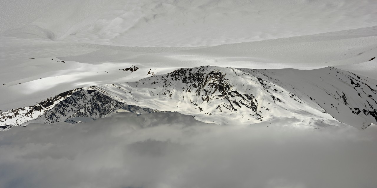 a snowy mountain top with clouds