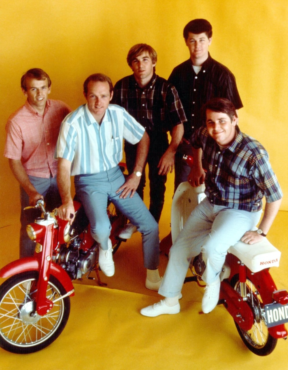 a band standing in a bright yellow room smiling at the camera