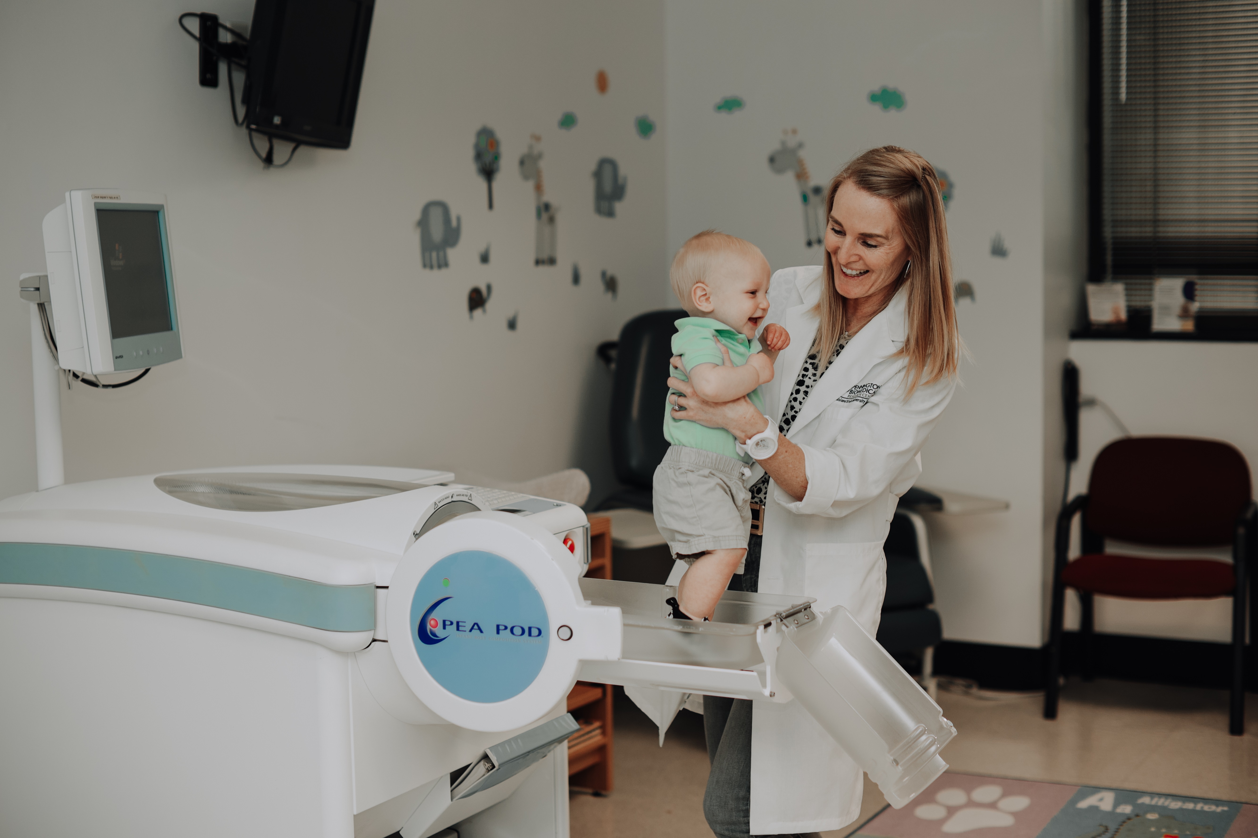 Professor Leanne Redman lifts a baby out of a Pea Pod device that measures body composition.