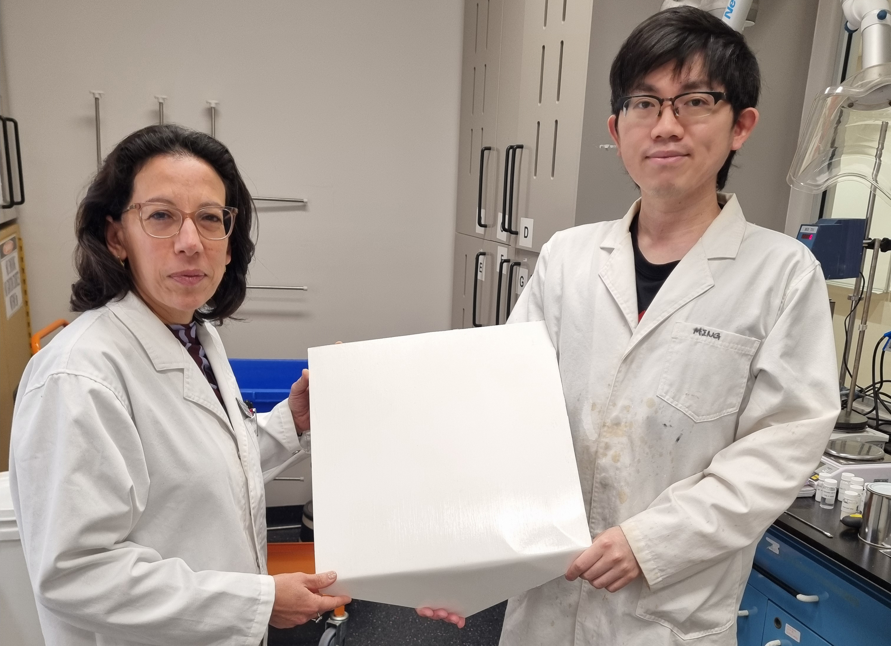 Scientists holding one of the experimental painted tiles