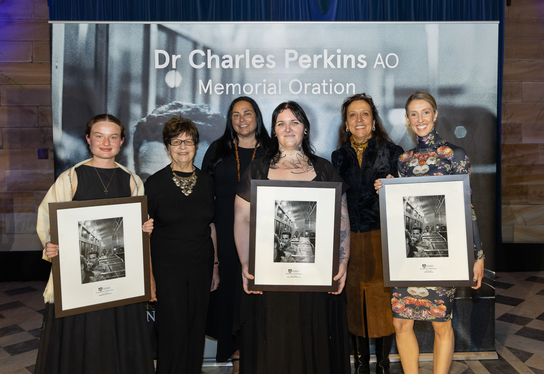 A group of women smiling for the camera, with three hold photo frames. 