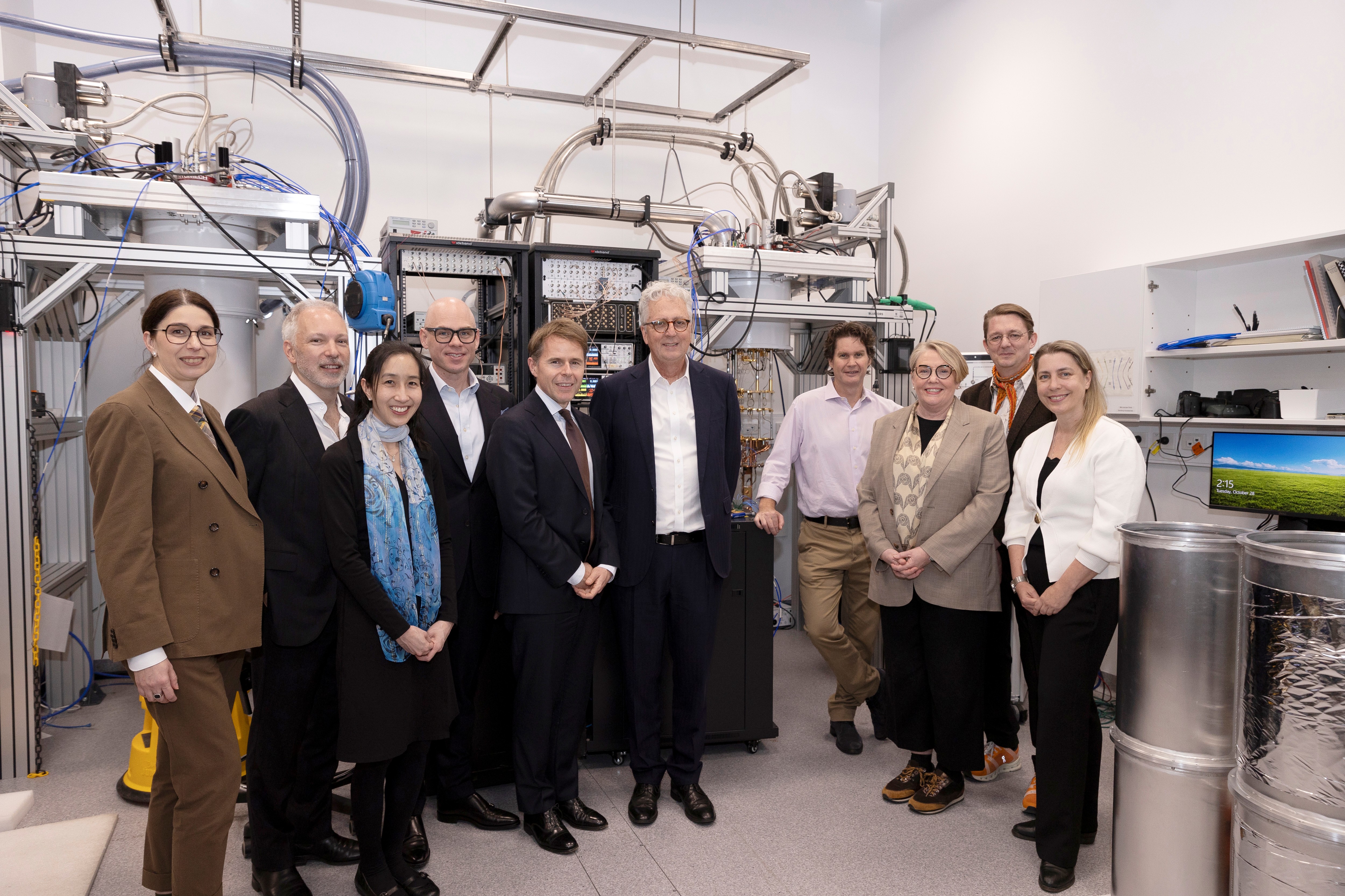 Group shot of scientists and business people in front of a quantum computer at the University of Sydney