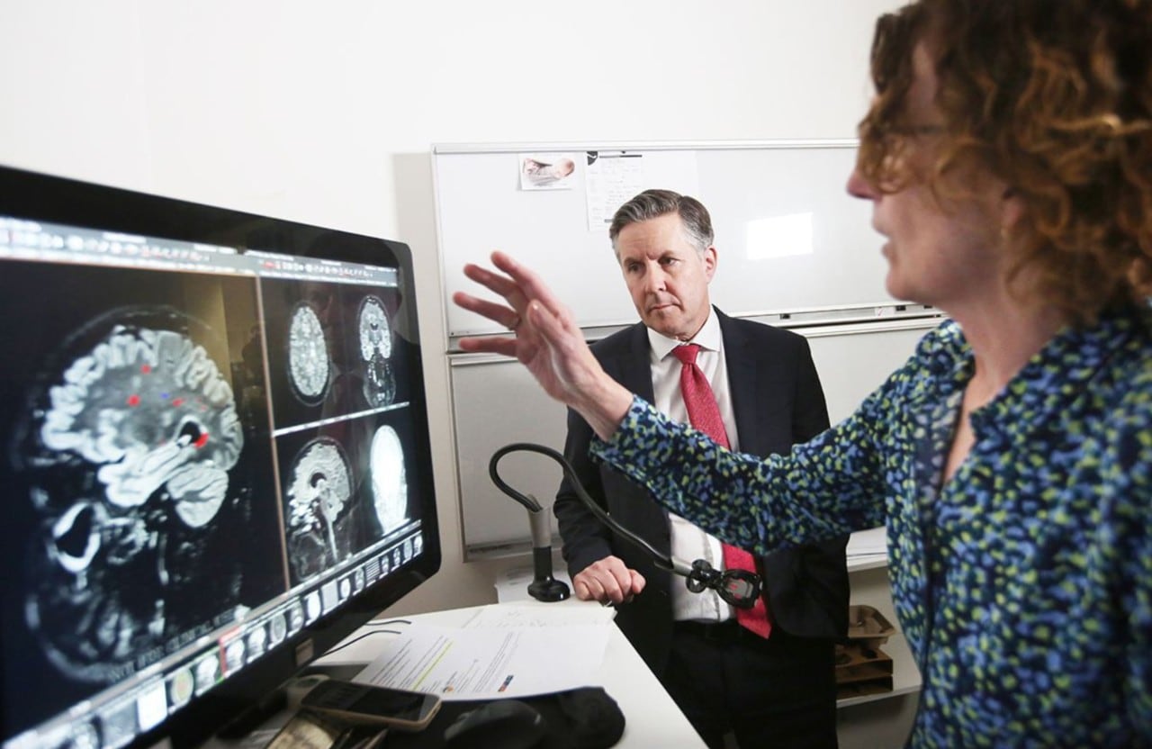 Researchers looking at a computer screen with images of brain scans on it