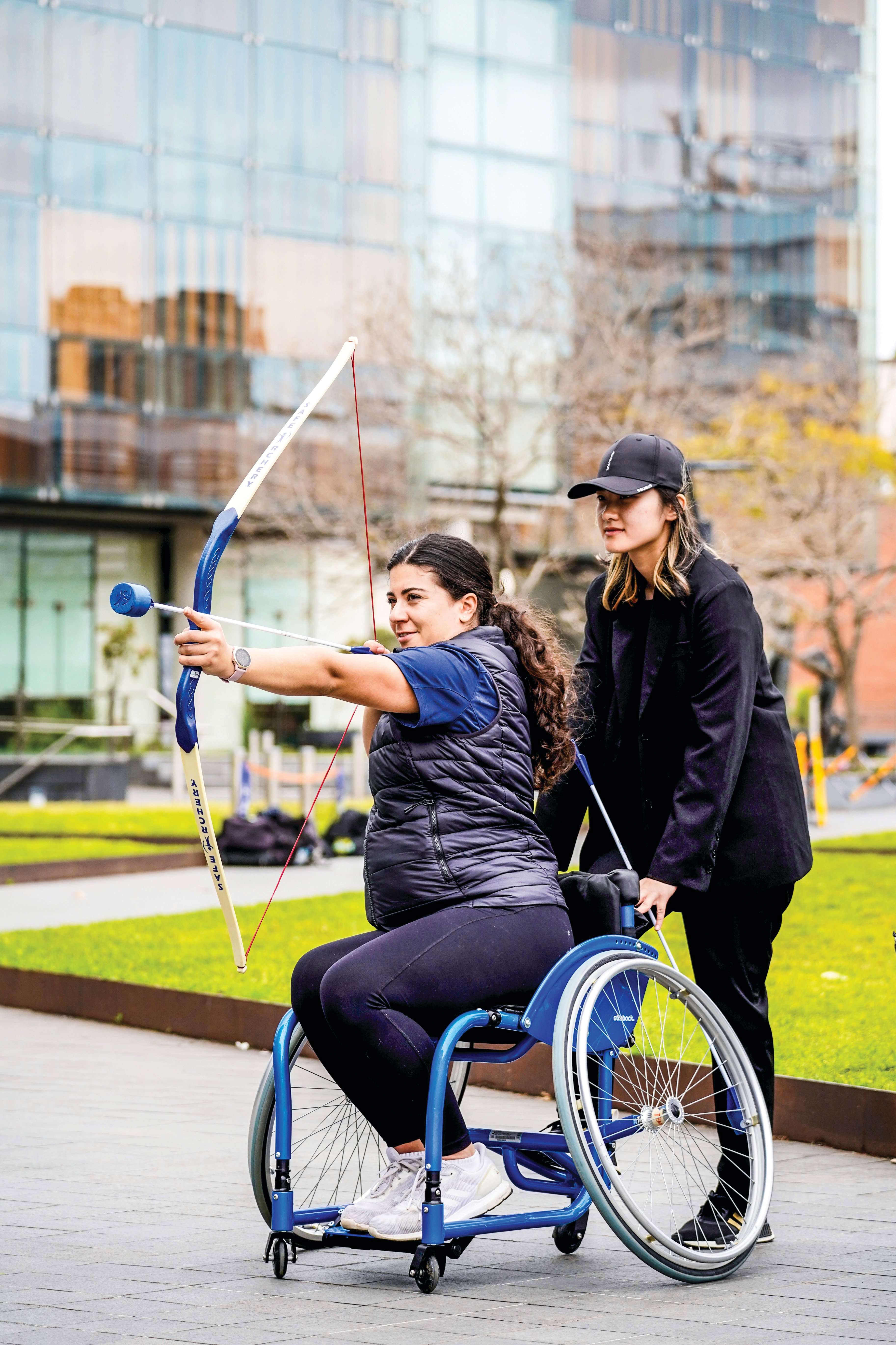 Pair of students, one in wheelchair holding a bow and arrow.