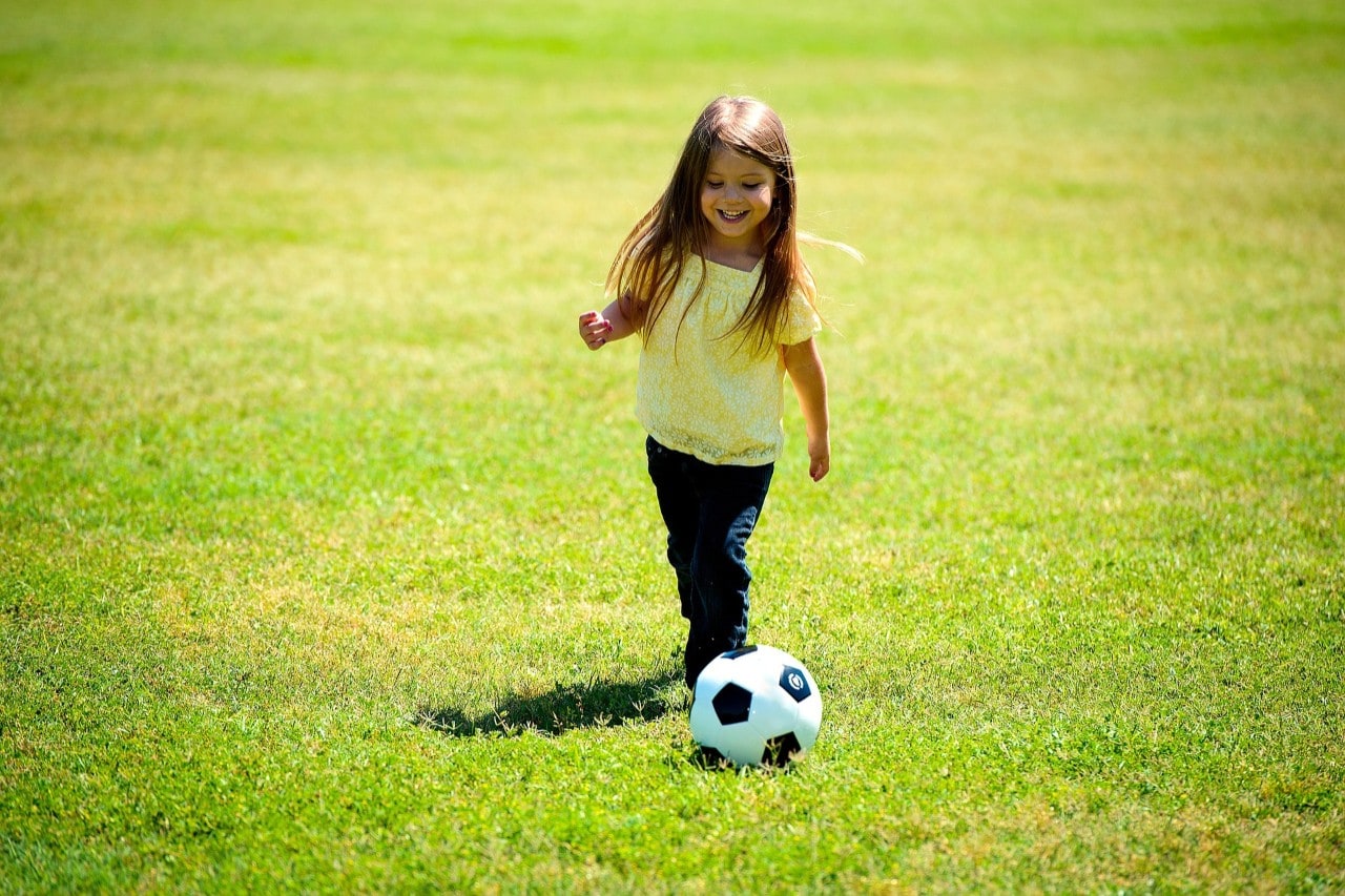 photo of a small girl kicking a soccer ball