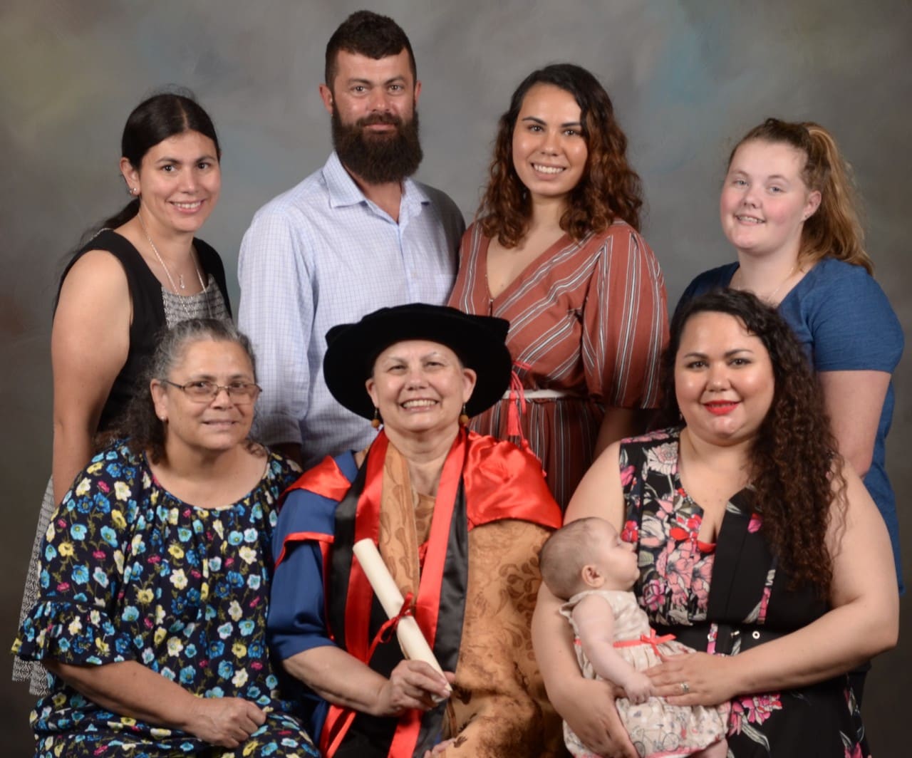 Lynette Riley photographed with her family. She is wearing a graduation cap and gown.