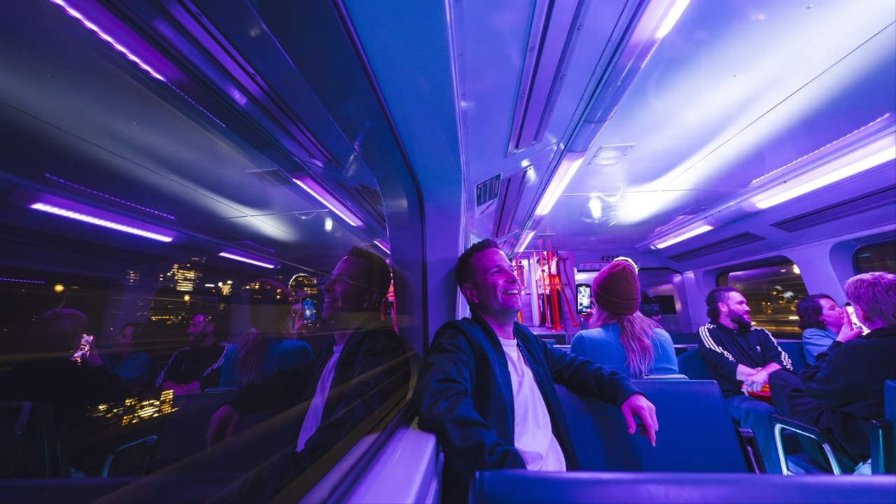 two men sitting inside a train that is flooded with purple lights
