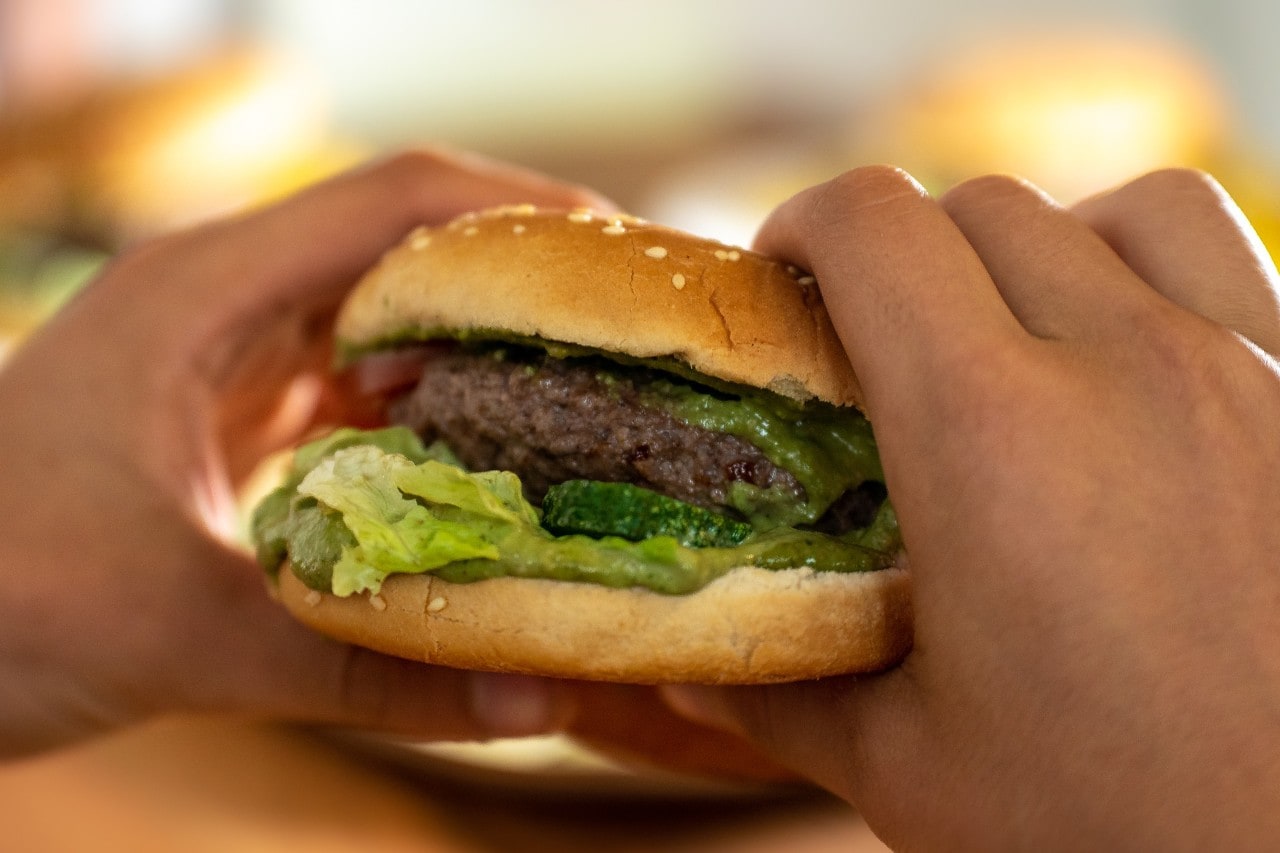 Hands holding burger with patty