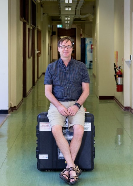 In the Physics Building Professor Iver Cairns sits on the box he used to send the INSPIRE-2 satellite to Holland