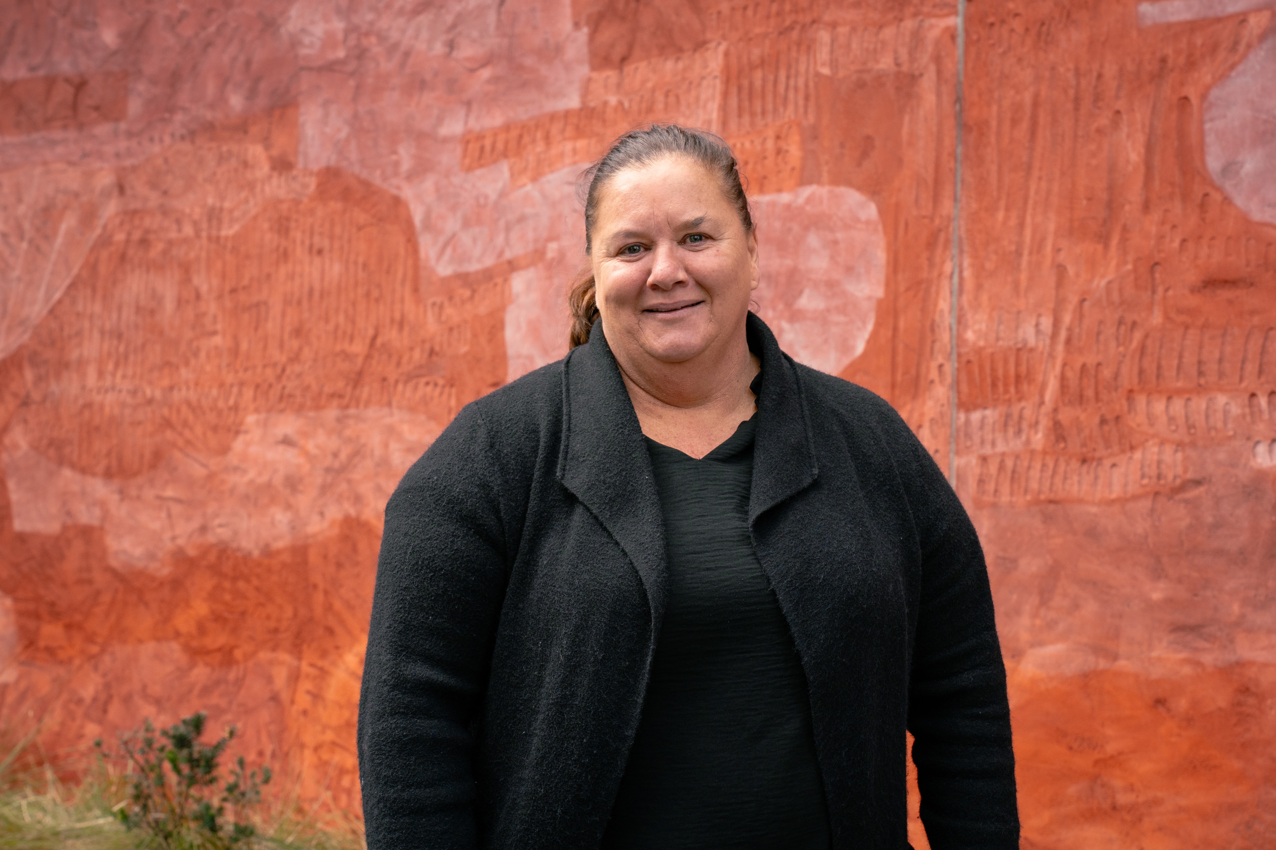 Wiradjuri Woman and Director Gadigal Centre. She is posed in front of Aboriginal artwork.