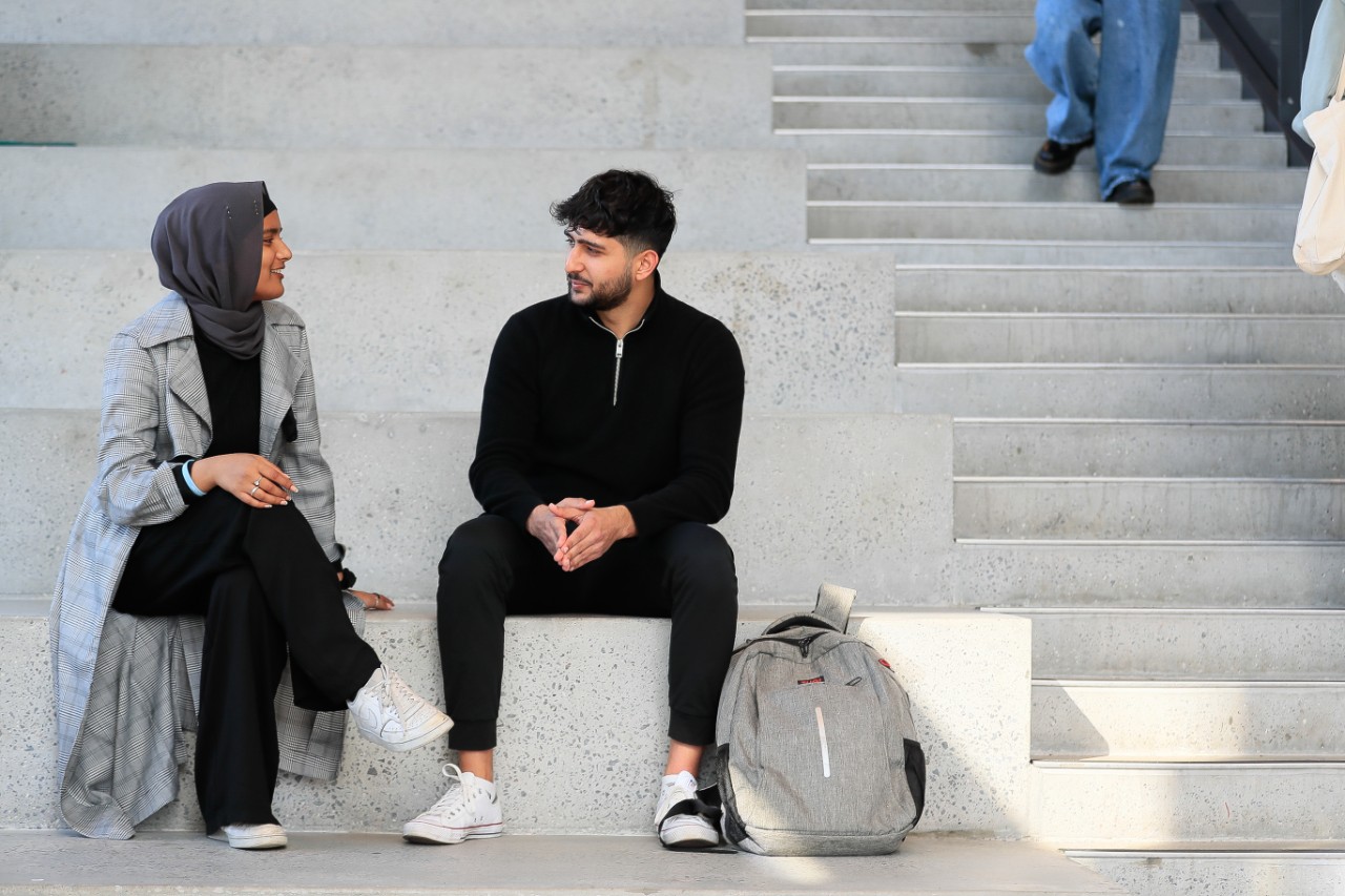 Two students talking to each other on large grey steps