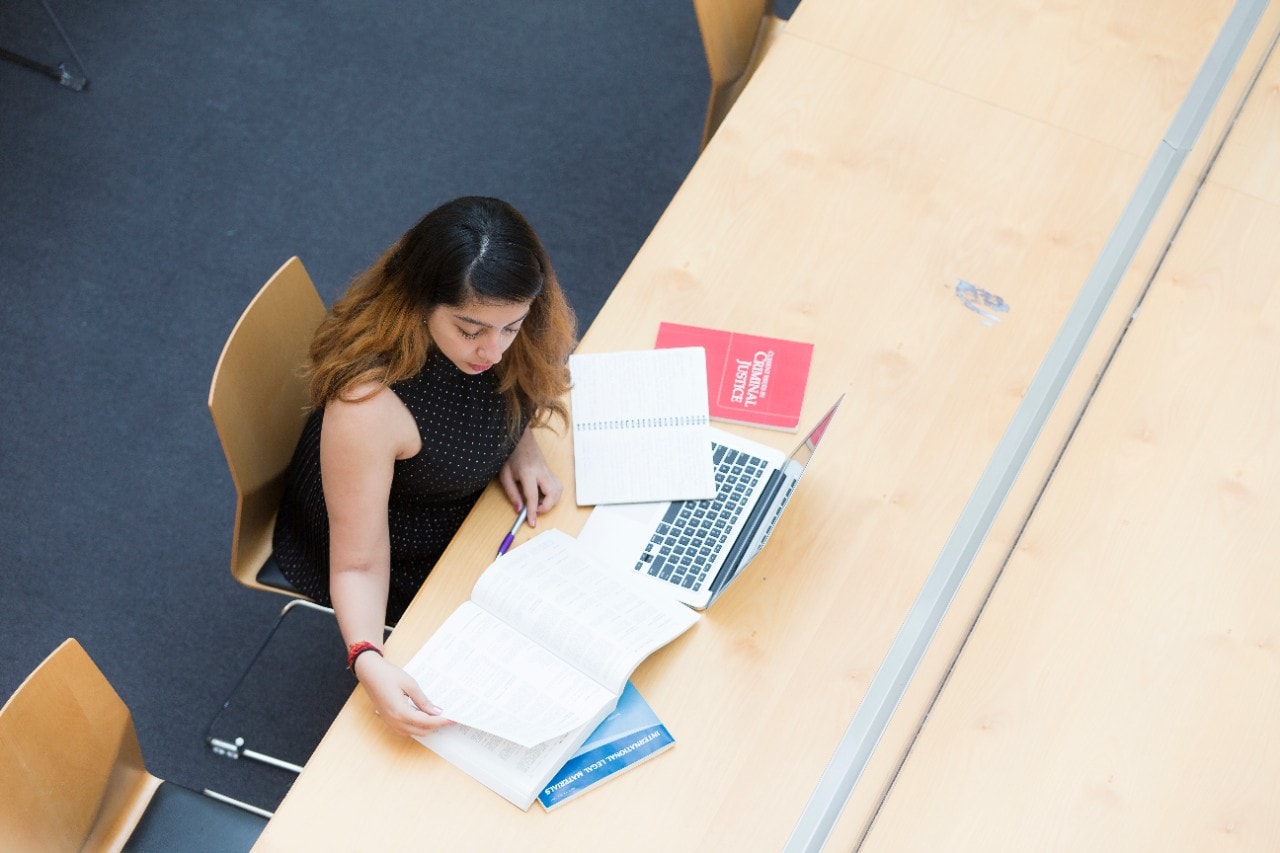 An overhead shot of a female student studying her notes at a large table