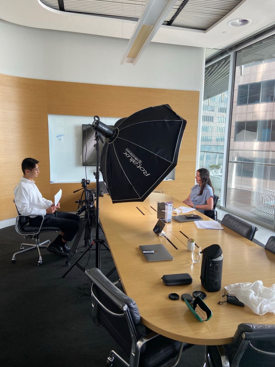 An office space with studio lighting, Jason Zhu He (left) interviews a subject for a web video.