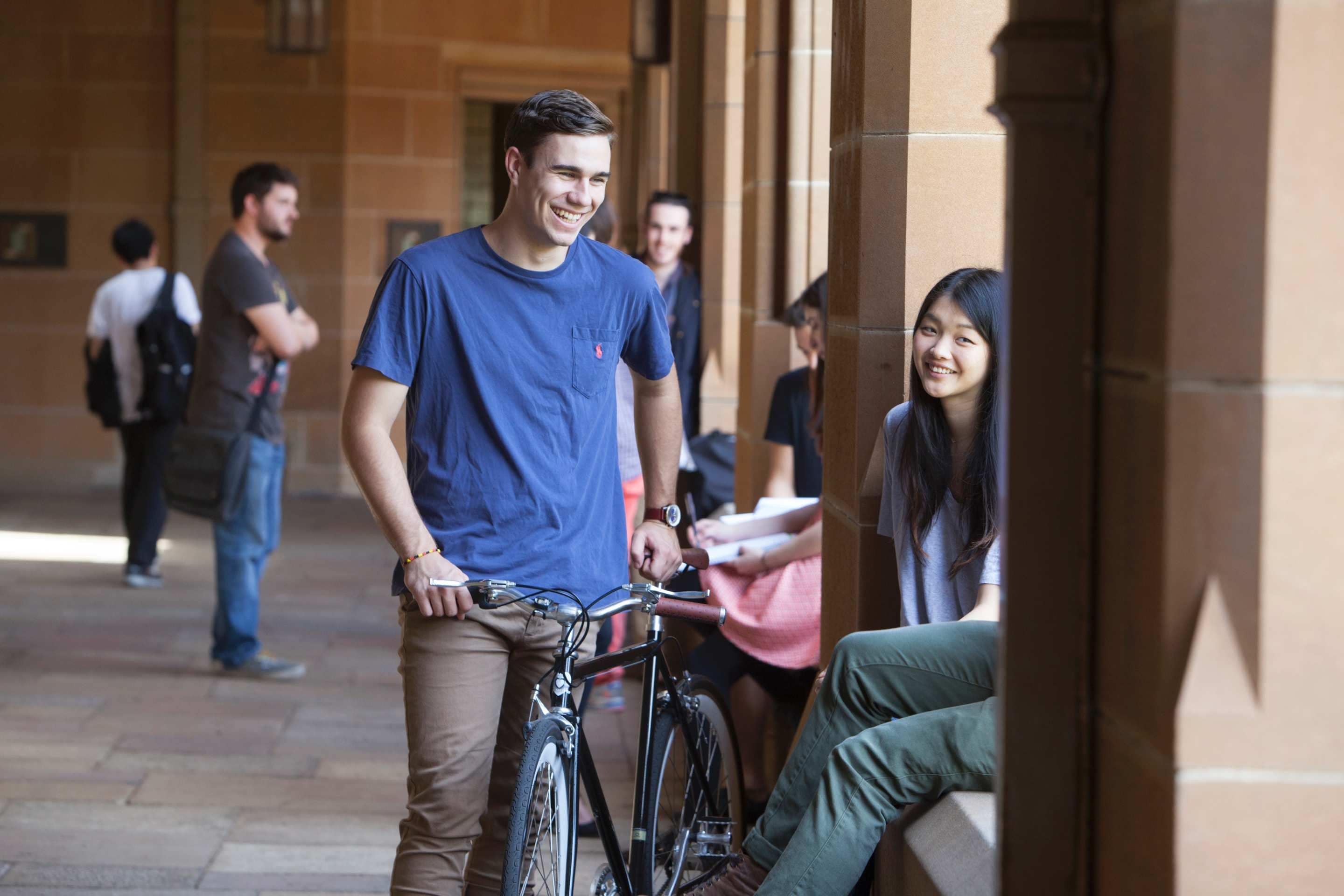 Students smiling in the quad with a bicycle