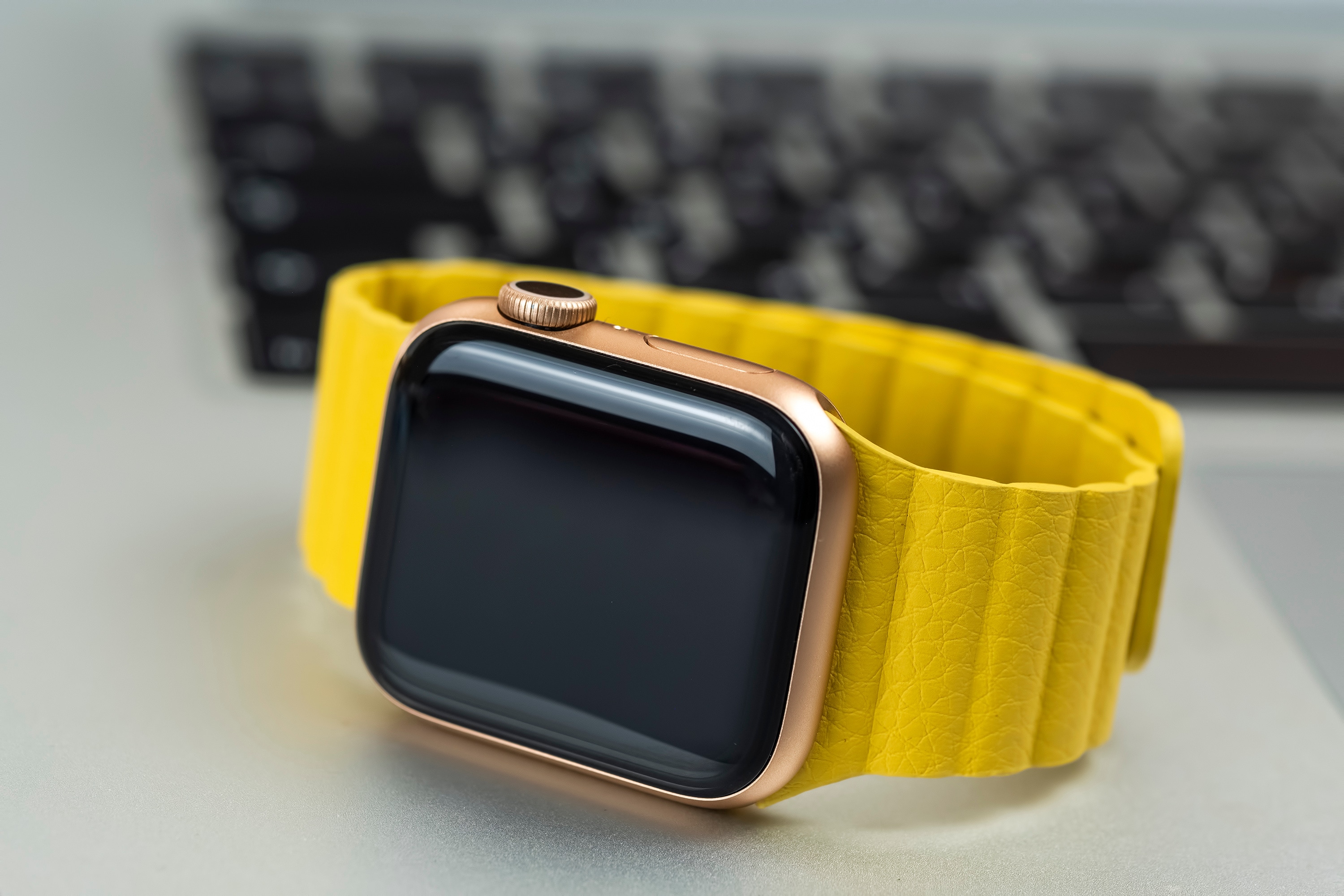 Minsk, Belarus - April 07, 2021: Apple Watch with yellow strap on laptop keyboard