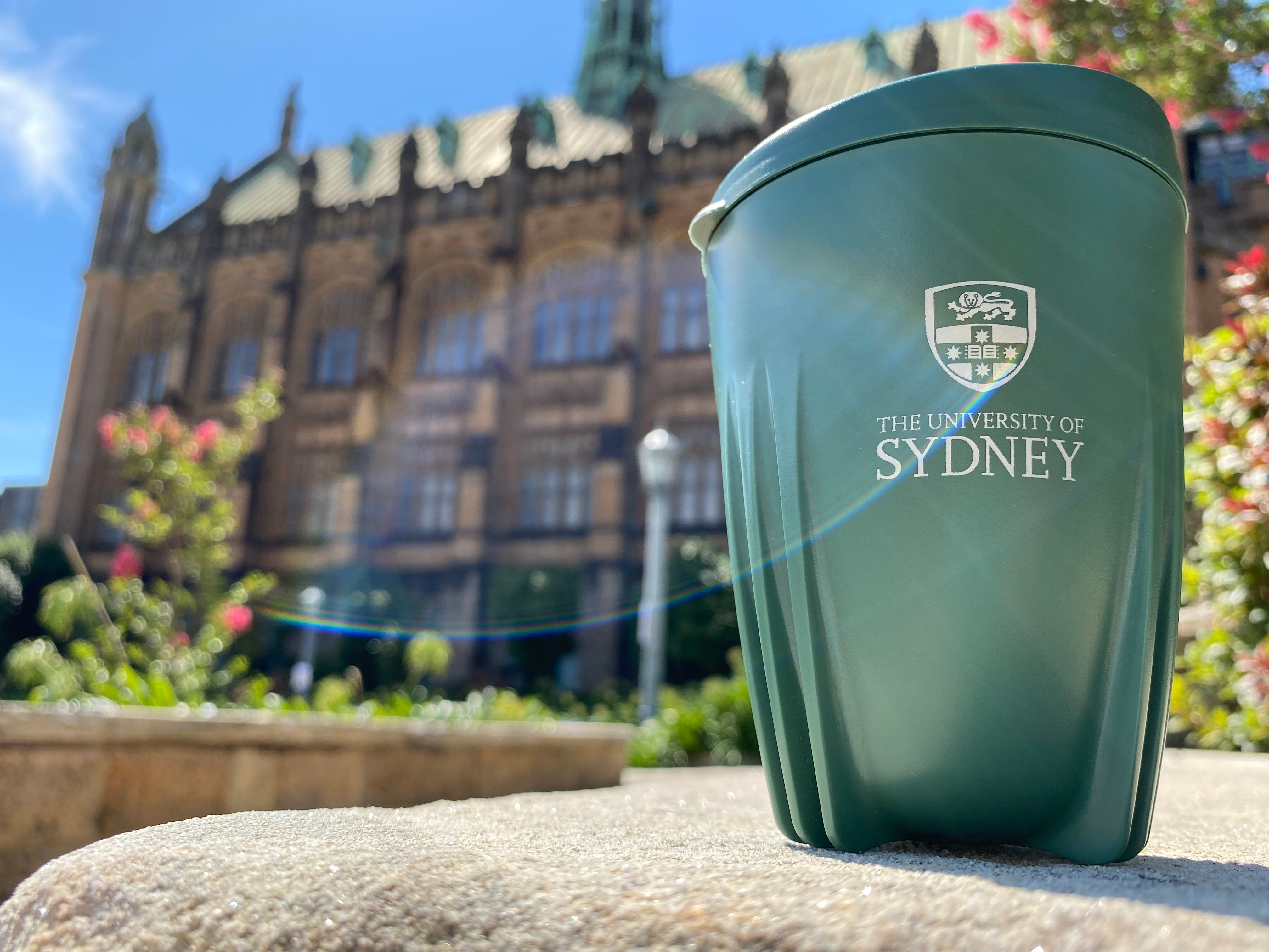 Green Caffeen cup with University building in background
